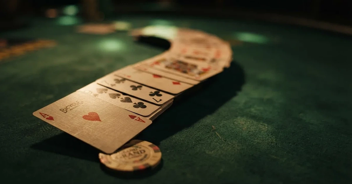A close-up of a shuffled deck of playing cards fanned out on a green felt table.